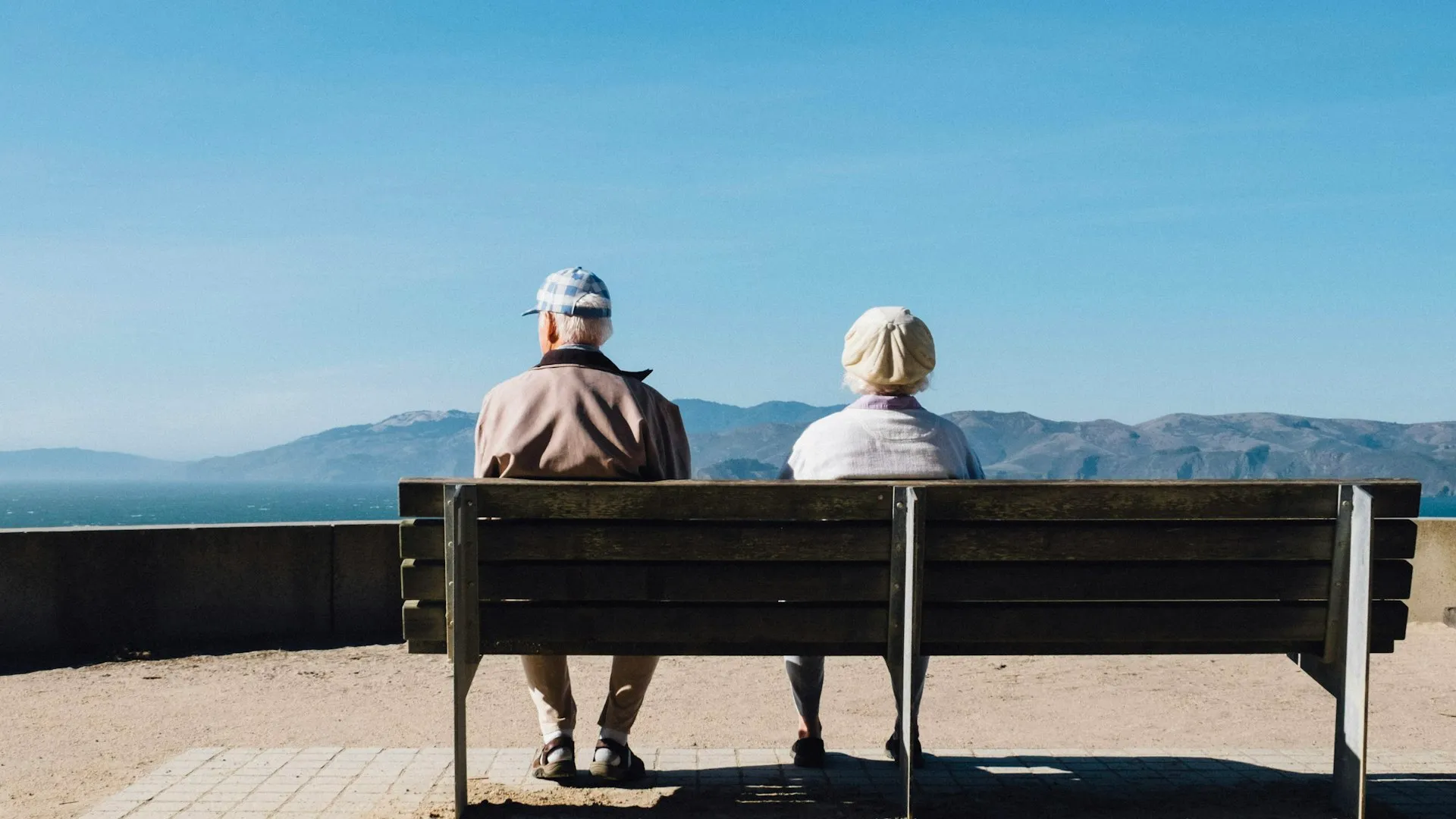Senior couple sitting peacefully on bench by the sea